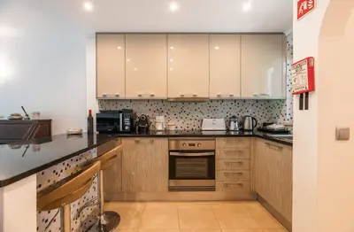 a kitchen with wooden cabinets and a stove top oven at Coastal Retreat with Pool and Beach Access by Drago Rentals in Albufeira