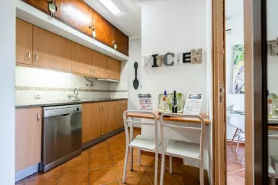 a kitchen with wooden cabinets and a table and chairs at Cosy by the pool in Quarteira