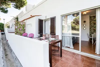 a dining table on the balcony of a house at Cosy by the pool in Quarteira