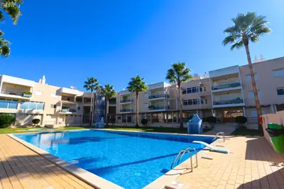 a swimming pool in front of a building with palm trees at Vilamoura, Marina Sol T2 in Vilamoura