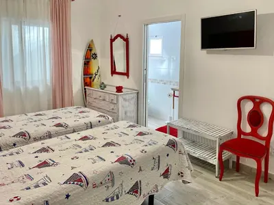a bedroom with two beds and a chair and a television at Bambus House Blue in Quarteira