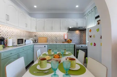 a kitchen with a table with plates and wine glasses at Bambus House Green in Quarteira