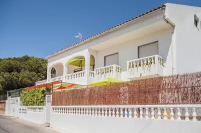 a white house with balconies and a fence at Bambus House Green in Quarteira