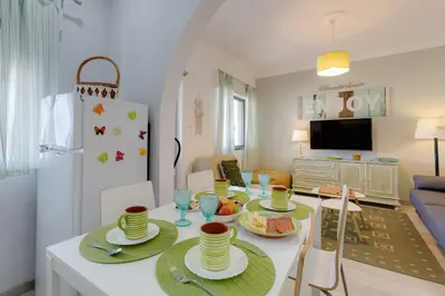 a kitchen and living room with a table with dishes on it at Bambus House Green in Quarteira