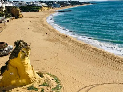 an aerial view of a beach with people walking on the sand at Deluxe apartment in Albufeira old town, 200m walk to beach, pool parking in Albufeira