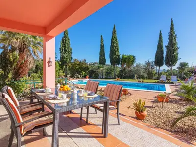 a patio with a table and chairs next to a pool at Villa Villa Rosa by Interhome in Loulé