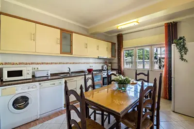 a kitchen with a table and a dining room at T2 Anastácio com vista Jardim in Olhos de Água