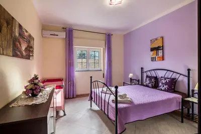 a bedroom with purple walls and a bed and a window at T2 Anastácio com vista Jardim in Olhos de Água