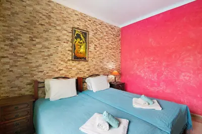 a bedroom with a blue bed and a pink wall at T2 Anastácio com vista Piscina in Olhos de Água