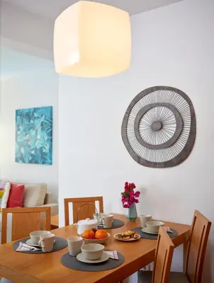 a dining room table with a fan on the wall at Casas Barulho Albufeira Marina in Albufeira