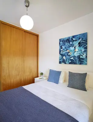 a bedroom with a king sized bed with a wooden wall at Casas Barulho Albufeira Marina in Albufeira
