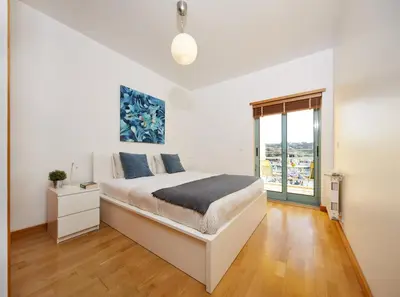 a white bedroom with a bed and a window at Casas Barulho Albufeira Marina in Albufeira