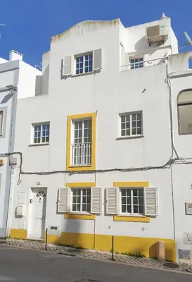 a white building with yellow accents on a street at Casa Albufeira in Albufeira