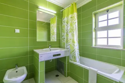 a green bathroom with a sink and a toilet at Villa Pacheco in Albufeira