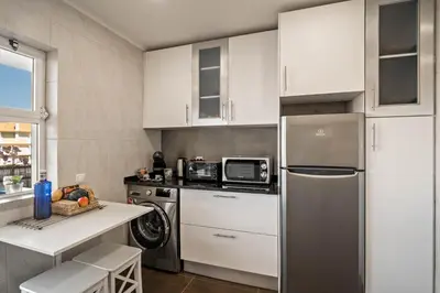 a kitchen with white cabinets and a stainless steel refrigerator at Vilamoura Boutique Apartment in Quarteira