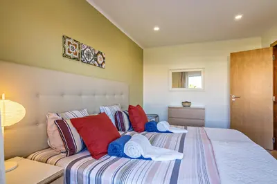a bedroom with a bed with red and blue pillows at Vilamoura Boutique Apartment in Quarteira
