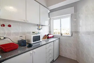 a kitchen with white cabinets and a television on a counter at Palmeira Galé in Galé