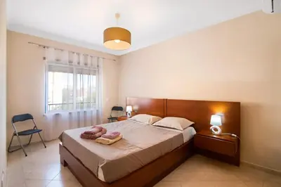 a bedroom with a large white bed with a wooden headboard at Almancil Park Apartment in Almancil