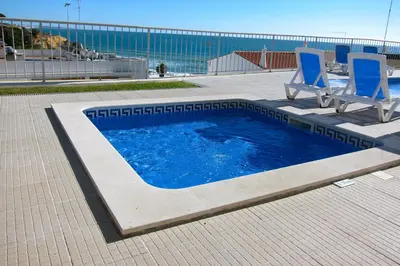 a swimming pool with two blue chairs and the ocean at Duplex Varandas Do Mar Patricia Vista Mar - 50 metros Praia Olhos de Água in Albufeira