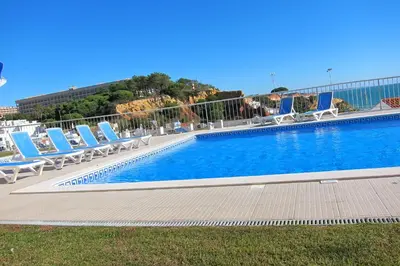 a large swimming pool with lounge chairs and a building at Duplex Varandas Do Mar Patricia Vista Mar - 50 metros Praia Olhos de Água in Albufeira