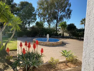 a fountain in a park with red flowers at Quinta Verde Albufeira in Albufeira