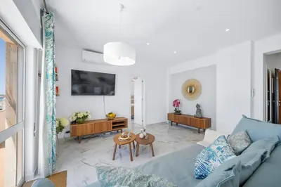 a living room with a blue couch and a table at Stylish Algarve Apartment with Spacious Terrace & Sea Views in Quarteira