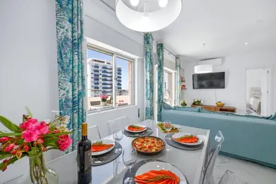 a dining room with a table with plates of food at Stylish Algarve Apartment with Spacious Terrace & Sea Views in Quarteira