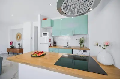 a kitchen with blue cabinets and a wooden counter top at Stylish Algarve Apartment with Spacious Terrace & Sea Views in Quarteira