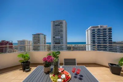 a balcony with a table with food and flowers on it at Stylish Algarve Apartment with Spacious Terrace & Sea Views in Quarteira