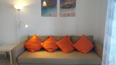 a couch with four orange pillows on it at T1 Torre 17 Vista Cidade in Quarteira