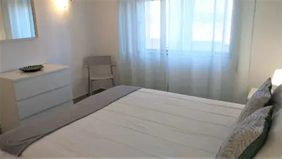 a bedroom with a large bed with a dresser and a window at T1 Torre 17 Vista Cidade in Quarteira