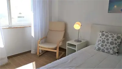 a bedroom with a bed and a chair and a lamp at T1 Mira Praia 7 - Remodelado, Ar-Condicionado, Vista Mar, Wifi in Quarteira