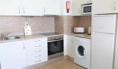 a kitchen with white cabinets and a washer and dryer at T1 Mira Praia 7 - Remodelado, Ar-Condicionado, Vista Mar, Wifi in Quarteira