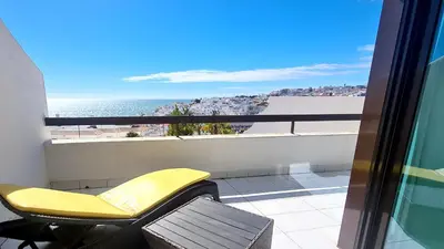 a yellow chair on a balcony with a view of the ocean at Beach lovers apartment 26 in Albufeira
