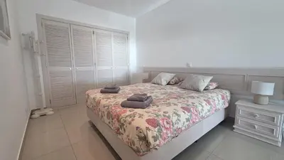 a bedroom with a bed and a nightstand and a window at Beach lovers apartment 26 in Albufeira