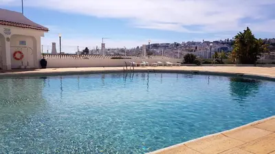 a large swimming pool with chairs and a building at Beach lovers apartment 26 in Albufeira