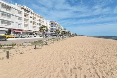 a sandy beach with a row of buildings and the ocean at Sail Away in Quarteira