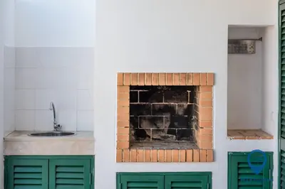 a kitchen with a brick fireplace with a sink at Vila Nico by MTPhomes in Albufeira