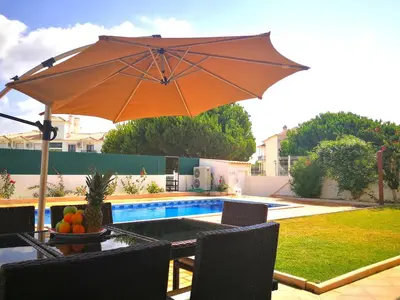 an umbrella sitting on a table next to a pool at Heated Pool 6 Bedroom Private Villa in Center of Olhos de Água in Albufeira