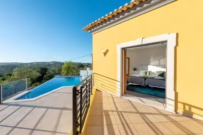 a bedroom villa with a pool and a bed on a balcony at Sunny House in Loulé