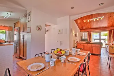 a kitchen and dining room with a wooden table at Villa Dela by Villa Plus in Albufeira