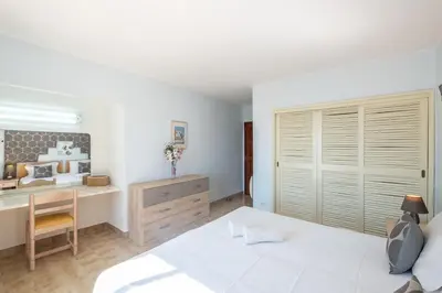 a white bedroom with a bed and a desk at Carolina Sea Apartment in Albufeira