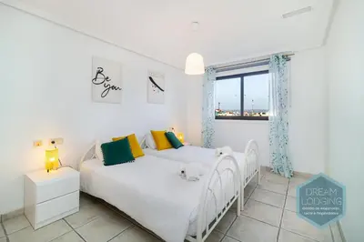 a white bedroom with two beds and a window at Falésia Park - Dream Lodging in Albufeira