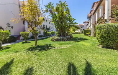 a yard with grass and trees and buildings at Sweet Old Village in Quarteira
