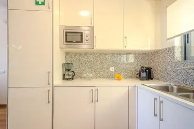 a white kitchen with white cabinets and a microwave at Jardins da Marina BI Albufeira Marina in Albufeira