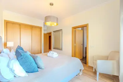 a bedroom with a large white bed with blue pillows at Jardins da Marina BI Albufeira Marina in Albufeira