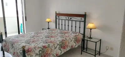 a bedroom with a bed with a floral bedspread and two lamps at Quarteira, Algarve - Seaview - Horizonte Mar in Quarteira