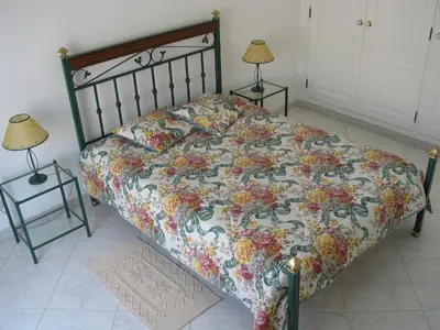 a bed with a floral comforter and two lamps at Quarteira, Algarve - Seaview - Horizonte Mar in Quarteira