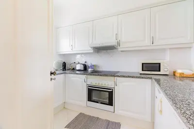 a white bedroom with a large bed with a window at Albufeira Family Holidays with Pool View in Albufeira