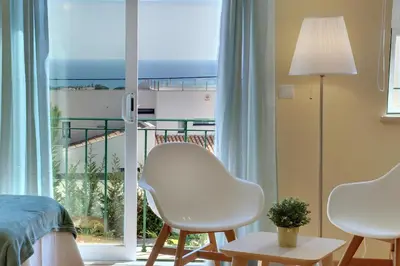 a bedroom with two white chairs and a balcony at Eagle Eye Villa in Albufeira